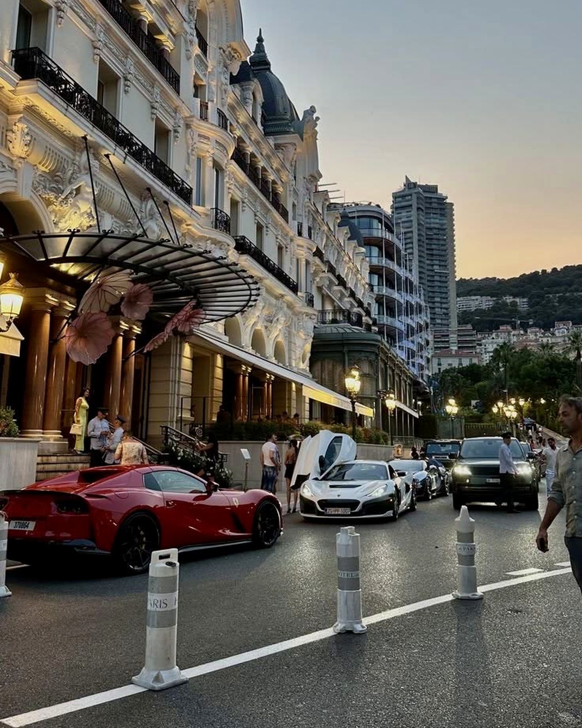 Fachada de hotel em Mônaco com carros de luxo estacionados ao entardecer